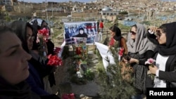 Members of an Afghan women's rights group hold flowers as they gather at the grave of Farkhunda, who was beaten with sticks and set on fire by a crowd of men in Kabul.