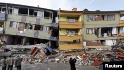 Earthquake survivors stand in front of a damaged building in Ercis on October 26.