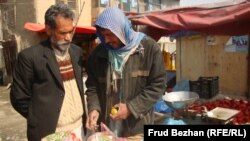 Mohammad Ahmadi (left) speaks to Ghulam, a local vegetable seller, at a campaign rally for Zalmai Rasul in Kabul on March 29.