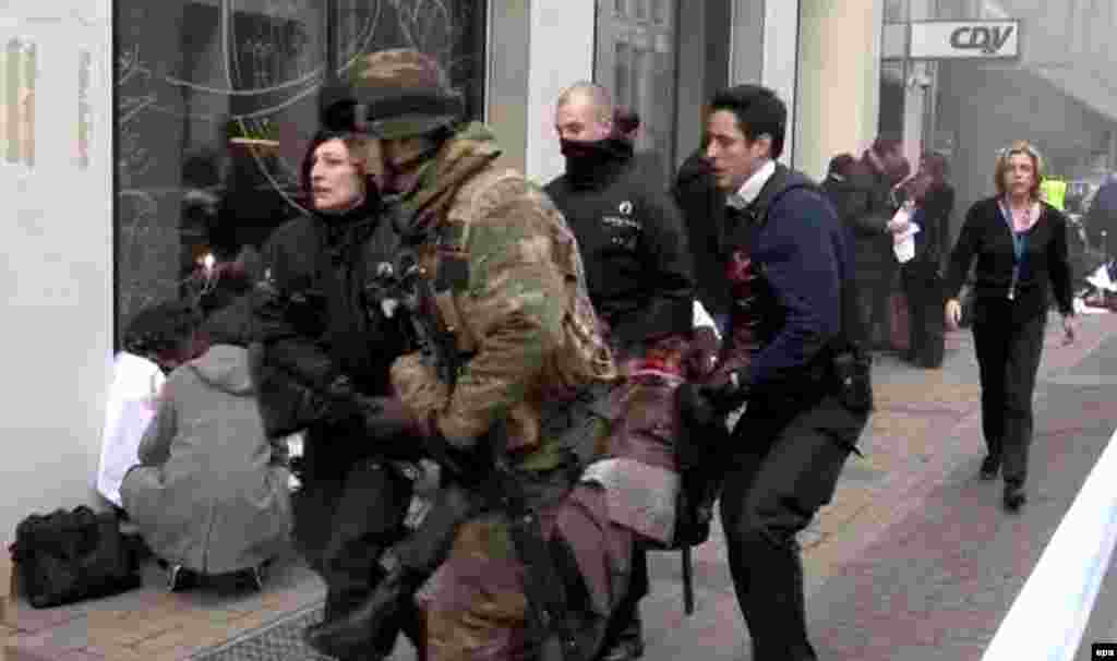 Belgian policemen and a soldier carrying an injured person after the explosion at Maalbeek station.