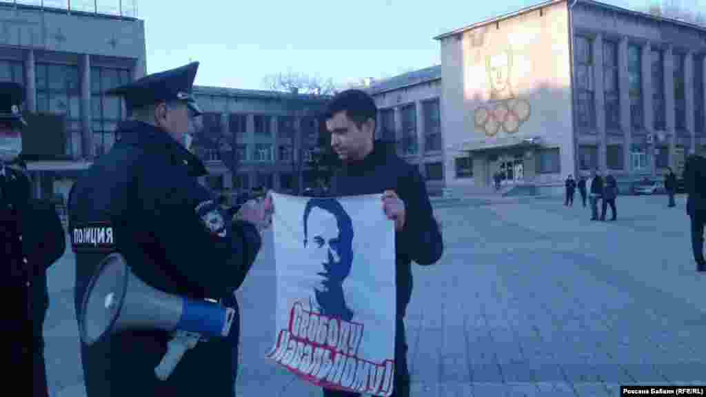 A police officer speaks with a protester holding a poster reading, &quot;Freedom for Navalny,&quot; in the Far East city of Komsomolsk-on-Amur.