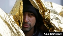 A migrant, wrapped in a thermal blanket, waits in line to get food at a migrant center in Bihac, Bosnia, close to the border with Croatia, on November 28.