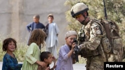 A British soldier shows his rifle to Afghan children during a patrol near the town of Lashkar Gah in Helmand Province. Most U.S. and British troops will be leaving the province by the end of 2014.