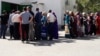 People wait in front of food stores in Ashgabat for their turn to buy basic staples at subsidized prices.