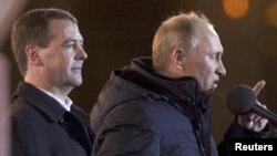 Vladimir Putin addresses supporters as outgoing President Dmitry Medvedev looks on at Manezh Square in Moscow on March 4.