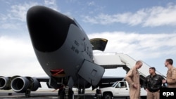 U.S. soldiers stand in front of a military planes at Manas in April.