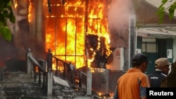 Men walk past a burning building in Osh as riots spread on June 11.