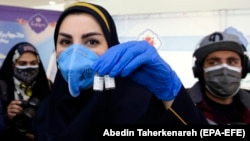 An Iranian health worker displays the Barekat vaccine to the media before a press conference in Tehran to announce the launch of the second and third phases of the human trials of the locally made vaccine in March.