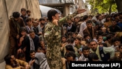 Afghans wait in front of a bank as they try to withdraw money in Kabul on September 12.