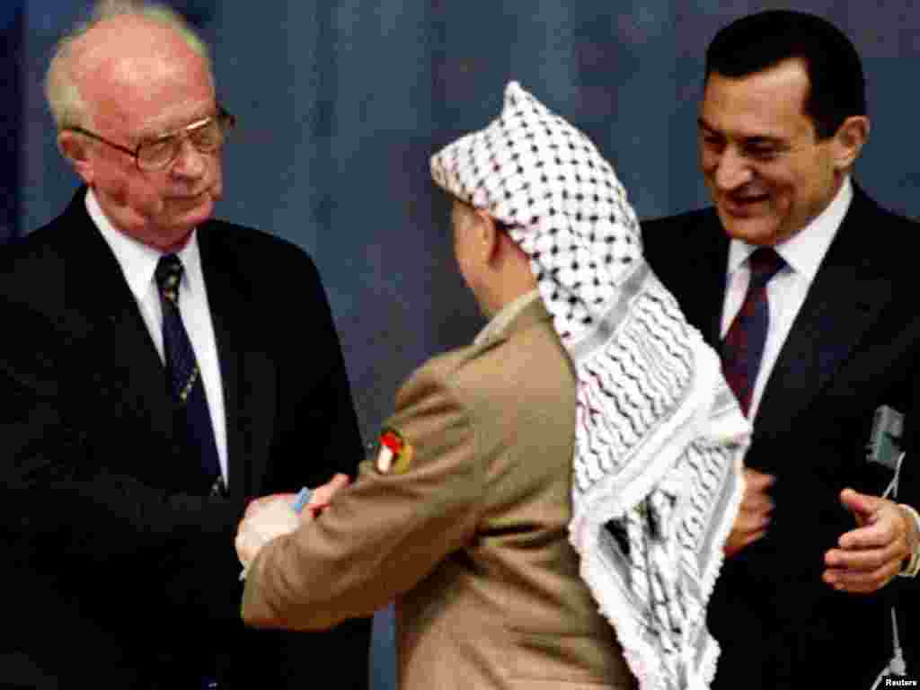 Mubarak looks on as Israel's Prime Minister Yitzhak Rabin (left) shakes hands with PLO Chairman Yasser Arafat. - Mubarak hosted the historic signing ceremony as Arafat signed the PLO-Israeli peace accords on limited Palestinian self-rule for the Gaza Strip and Jericho in Egypt on May 4, 1994.