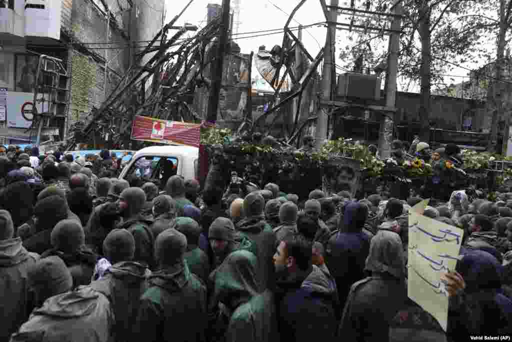 The funeral procession of a Islamic Revolutionary Guards Corps member killed in the recent protests in Shahriar, on the western edge of Tehran. Buildings in the background were also damaged in the protests.&nbsp;