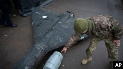 A Ukrainian officer points to a thermobaric charge from a downed Shahed drone launched by Russia from an undisclosed location in Ukraine.