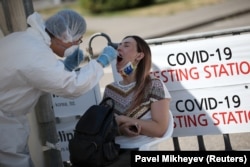 A health worker takes a swab from a woman at a mobile-testing station for the coronavirus in Almaty. Many Kazakh hospitals are running out of beds because of the growing number of people being admitted with COVID-19 symptoms.