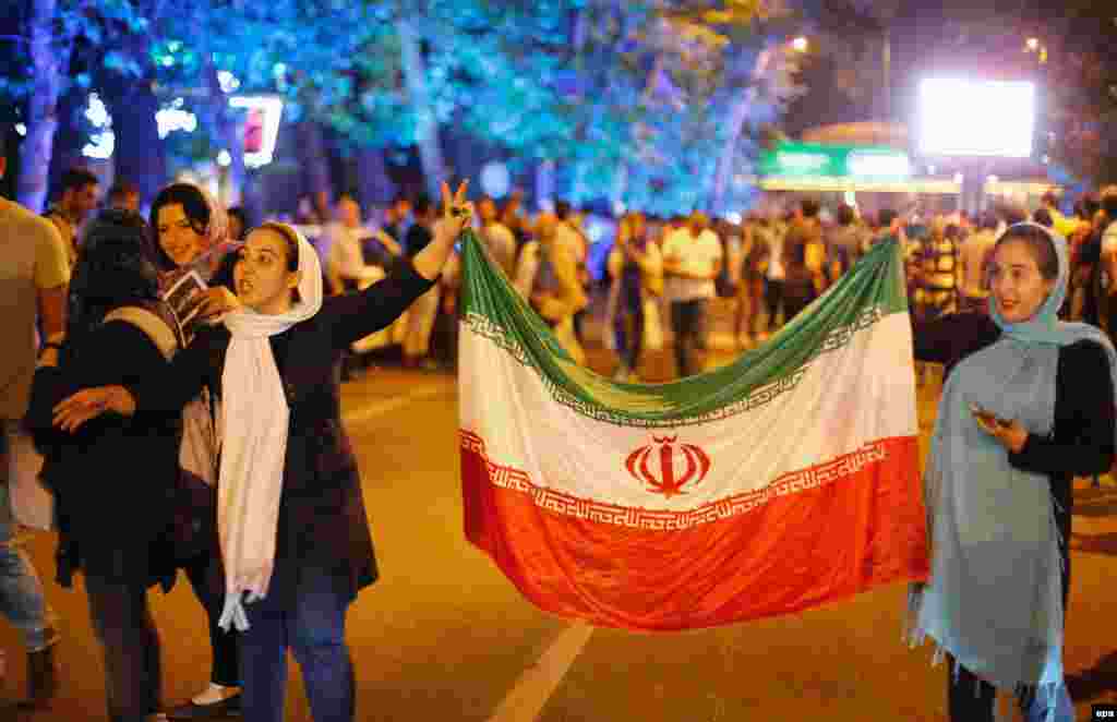 Women carry the Iranian flag.