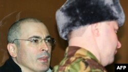 Mikhail Khodorkovsky (left) stands inside the bulletproof glass defendents' cage in a Moscow court on March 3.