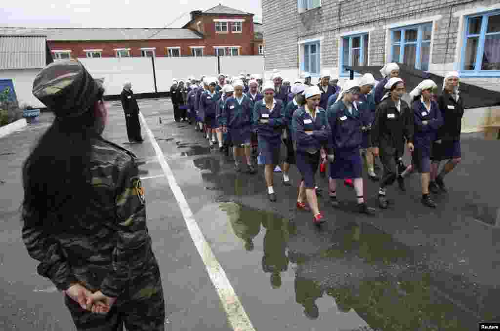 A female prison guard watches over inmates in the yard of a prison camp in the Siberian city of Krasnoyarsk.