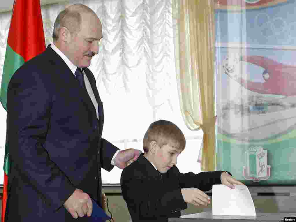 Lukashenka stands next to Kolya as he casts his ballot for president for him at a polling station in December 2010.