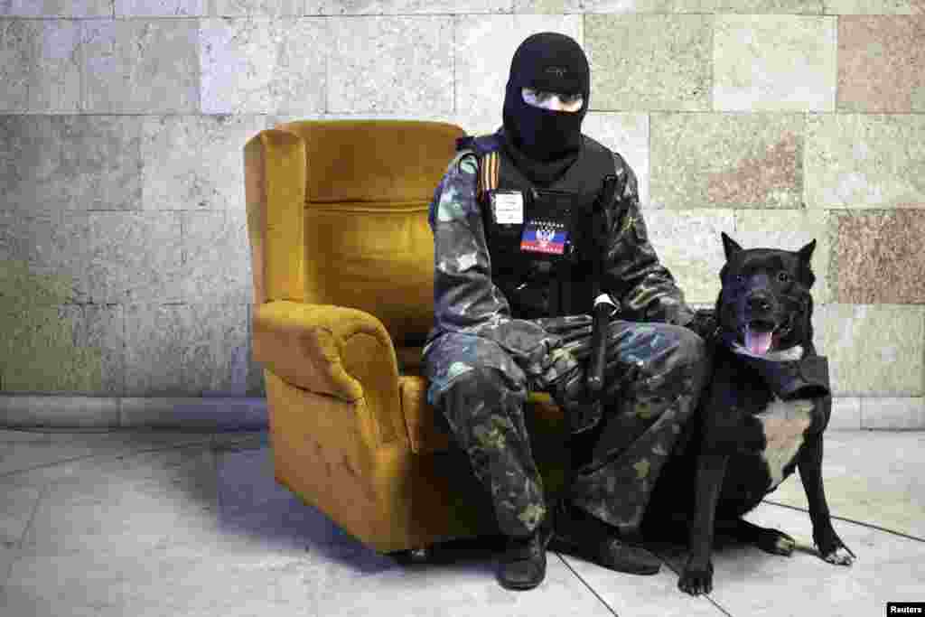 A masked pro-Russian separatist sits beside a dog as he poses for a picture inside an occupied regional government building in Donetsk in April 2014.