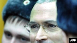 Mikhail Khodorkovsky stands between police officers at a courtroom in Moscow on December 27.