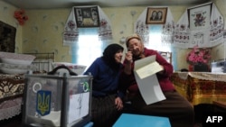 Two women in the village of Rusaki check a ballot in Ukraine's parliamentary elections on October 28.