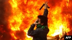 An opposition supporter gestures next to a burning police motorcycle set on fire during clashes with security forces in Tehran on December 27.