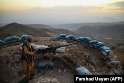 An Afghan militia fighter keeps watch at an outpost against Taliban insurgents in the Charkint district of Balkh Province on July 11.