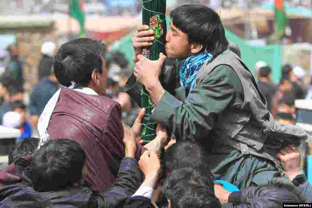 Boys kiss a holy flag that is traditionally raised on Norouz to mark the New Year.