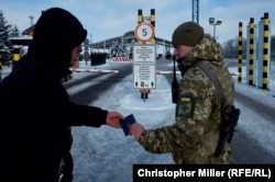 A Ukrainian border guard officer checks the passport of a Ukrainian man traveling to Russia through the Hoptivka border on November 29.