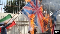 Iranians burn U.S., British, and Israeli flags at the inauguration of an anti-U.S. panel on the wall of the former U.S. Embassy in Tehran on September 2, 2015.