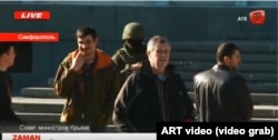 Reshat Ametov (right) stands near a masked Russian soldier and a man wearing a red armband typical of the so-called "self-defense" forces shortly before the Crimean activist's abduction in March 2014.