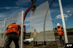 Workers build a fence to protect the Channel Tunnel site from migrants near Calais on August 5.