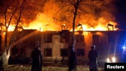 Riot police look on as firefighters try to extinguish fires after mass protests in the town of Ismayilli on January 24.