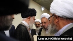 Iran's Supreme Leader Ayatollah Ali Khamenei (center) meets with clerics. "People ask, 'Why are [clerics] silent about [the problems]?' Silence means satisfaction," cleric Abdolhamid Massumi Tehrani, a critic of the establishment, told RFE/RL.