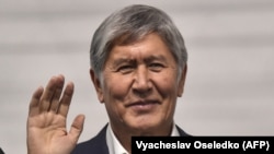 Ex-President Almazbek Atambaev waves as he stands inside a defendants' cage during a court hearing in Bishkek on November 27.