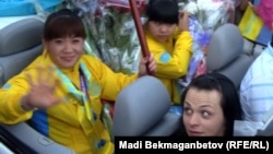 Kazakh weightlifters Maiya Maneza (left), Zulfiya Chinshanlo (center), and Svetlana Podobedova (right) are welcomed at Almaty airport in August 2012.