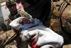 An Afghan soldier carries an injured baby from the hospital after the attack in Kabul on May 12.