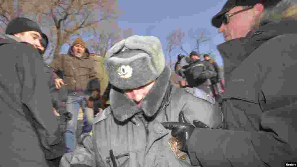 A policeman tries to escape from demonstrators during a protest in the far eastern city of Vladivostok.