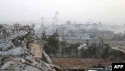 Syrian regime forces gather at the Kindi Hospital as smoke billows following air strikes on Aleppo on October 2.