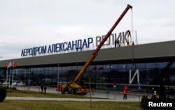 Workers dismantle an "Alexander the Great" sign from the airport in Skopje on February 24 as a gesture of goodwill toward Greece.