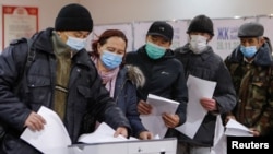 Voters stand in line before casting their ballots at a polling station during the parliamentary election in Bishkek on November 28.