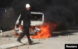 A man walks past a burning car set on fire by ethnic Albanians during a protest in the ethnically divided town of Mitrovica in northern Kosovo. (file photo)