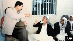 Saddam Hussein (left) drinks tea with elders in Mosul in 1993.