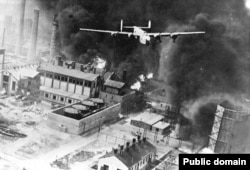 A U.S. B-24 bomber swoops above a burning oil refinery in Ploiesti in 1943.