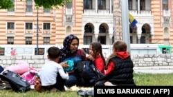 A migrant woman with children rests in the park across from city hall in Sarajevo.