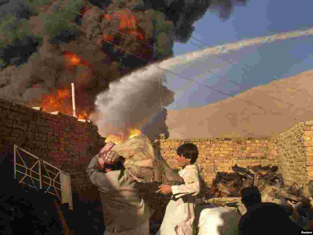 Men remove logs near the site of burning oil tankers that were carrying supplies to foreign forces in Afghanistan after they were attacked on the outskirts of Quetta in October 2010.