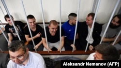 Ukrainian sailors sit inside the defendants' cage prior to a hearing at a court in Moscow on July 17.