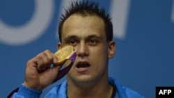 Kazakhstan's Ilya Ilyin posing on the podium with his gold medal after victory