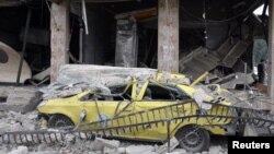 A damaged car lies among rubble after an explosion in the Al-Zahraa neighborhood of Homs in May 2017.