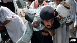 A security guard carries an injured blast victim as he arrives at a hospital in Peshawar.