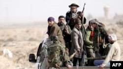 Rebel forces ride on the back of a pick-up truck in Ajdabiya, Libya, on March 2.